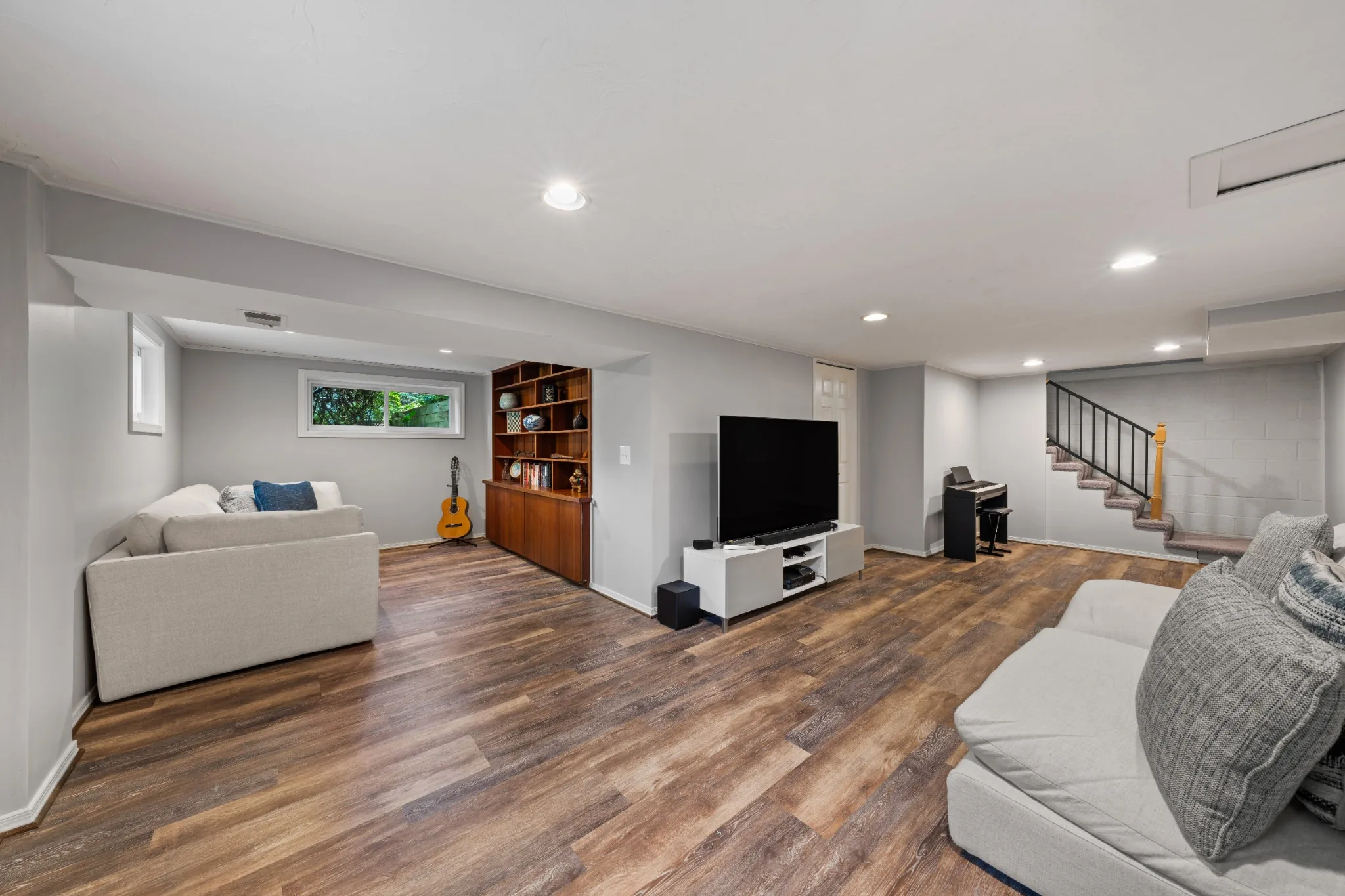 Finished lower-level living area with wood flooring