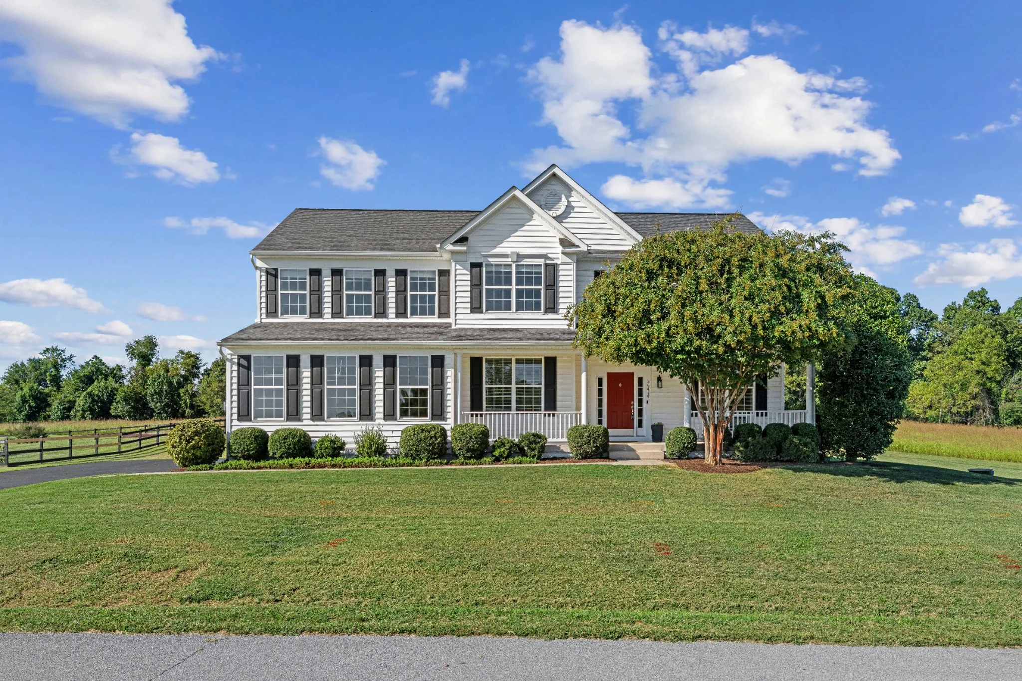 White two-story home and broad front lawn under a blue sky