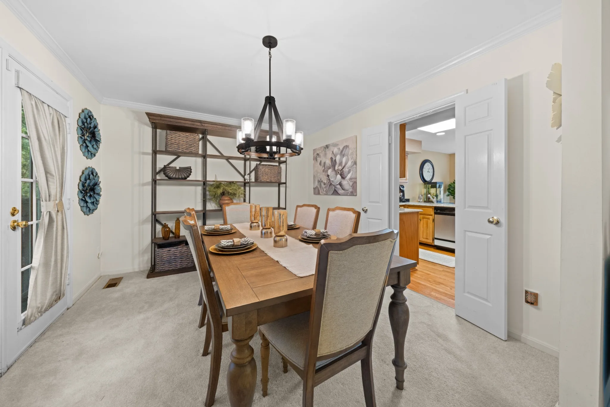 Bright dining room with table, chandelier, and view into the kitchen